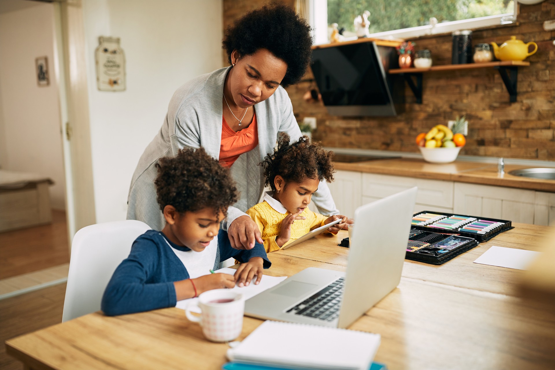 African American mother assisting her kids in learning at home.